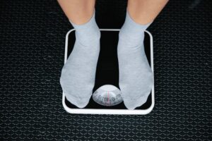 A photo of a person, ankles down, stepping on a scale in socks